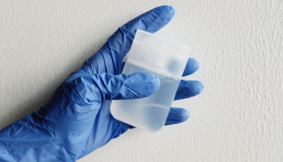 person in blue gloves holding clear plastic ontainer wonder does bleach and vinegar mix