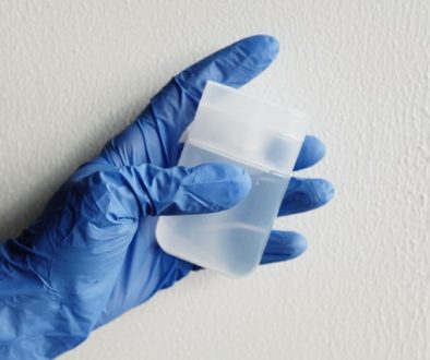 person in blue gloves holding clear plastic ontainer wonder does bleach and vinegar mix