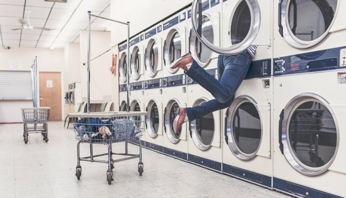 person with legs sticking inside washing machine searching for a laundry bag for washing machine